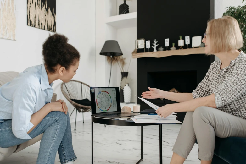 two women sitting on a couch in a living room, pexels contest winner, sitting on a desk, with a kid, charts, psychological