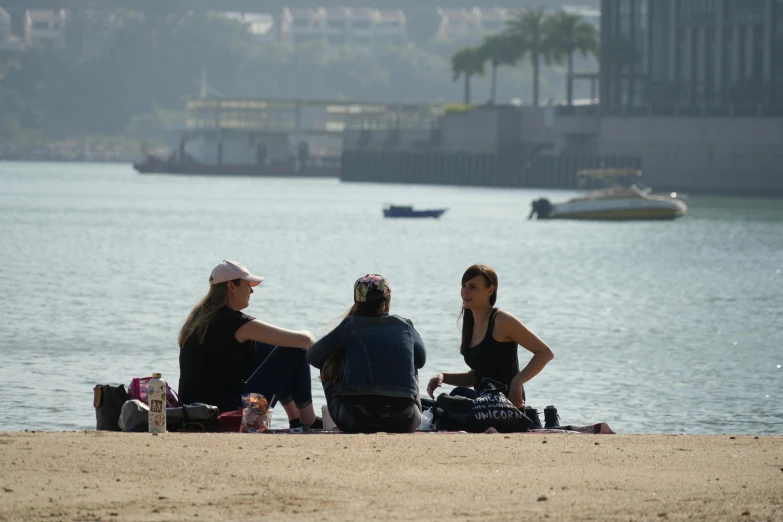 three people on the beach eating and talking