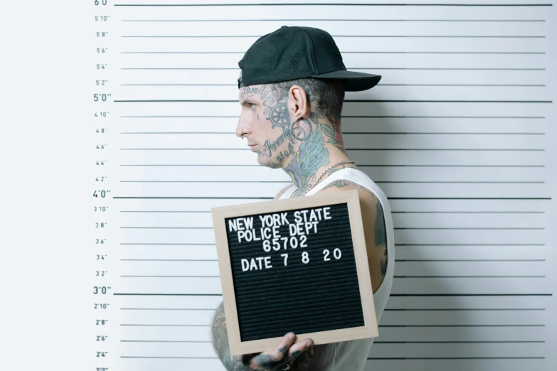 a man with tattoos holding up a sign, trending on pexels, mugshot, nypd, matte print, videogame still