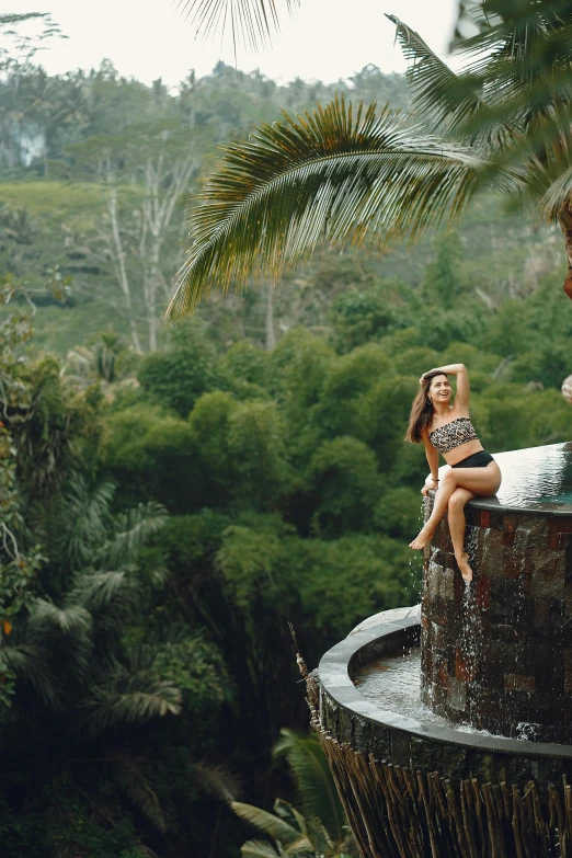 a woman in a bikini sitting on top of a fountain, by Julia Pishtar, sumatraism, floral jungle treehouse, panoramic shot, water temple, lush valley