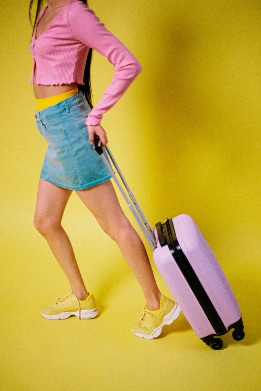 young lady pulling suitcase from yellow wall