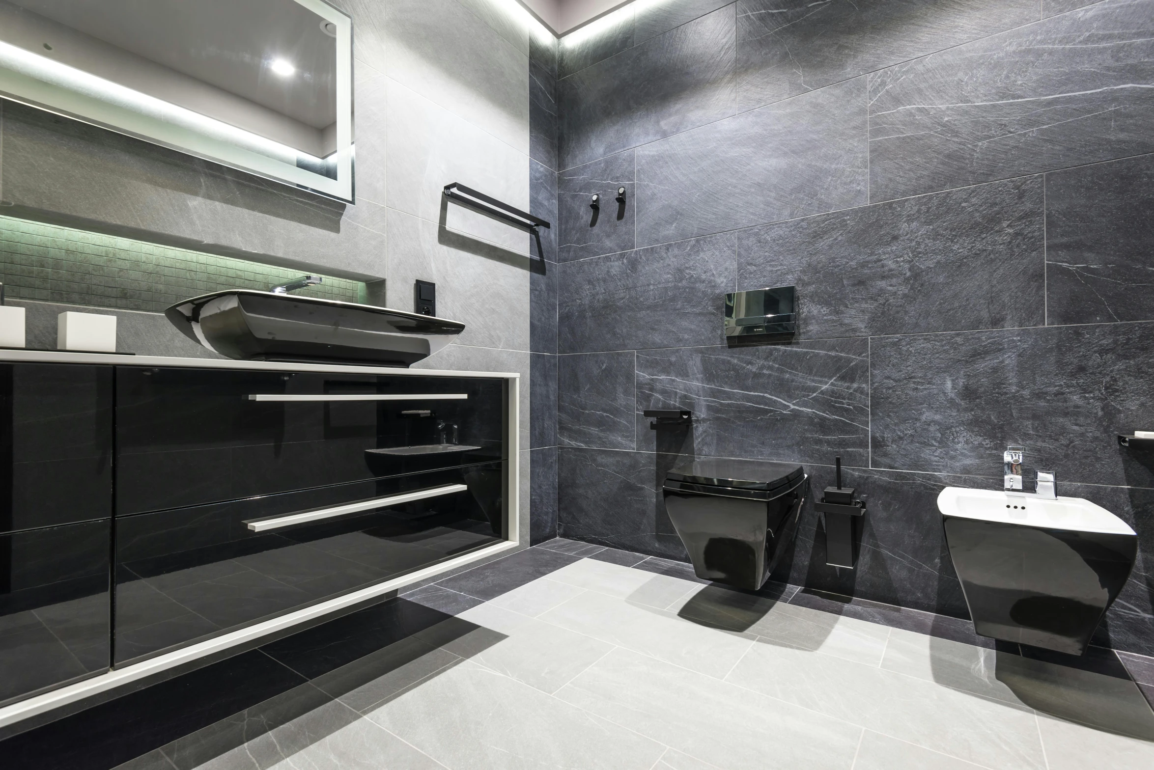 the modern bathroom has a white sink and two black toilets