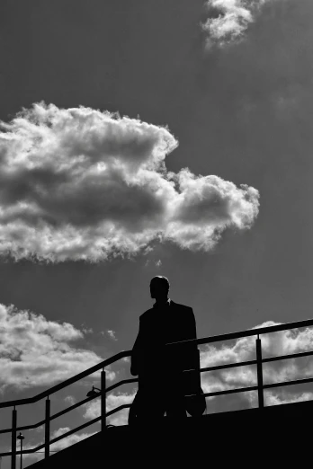 a couple of people standing on top of a bridge, inspired by Louis Stettner, ceremonial clouds, silhouette :7, man standing, sad man