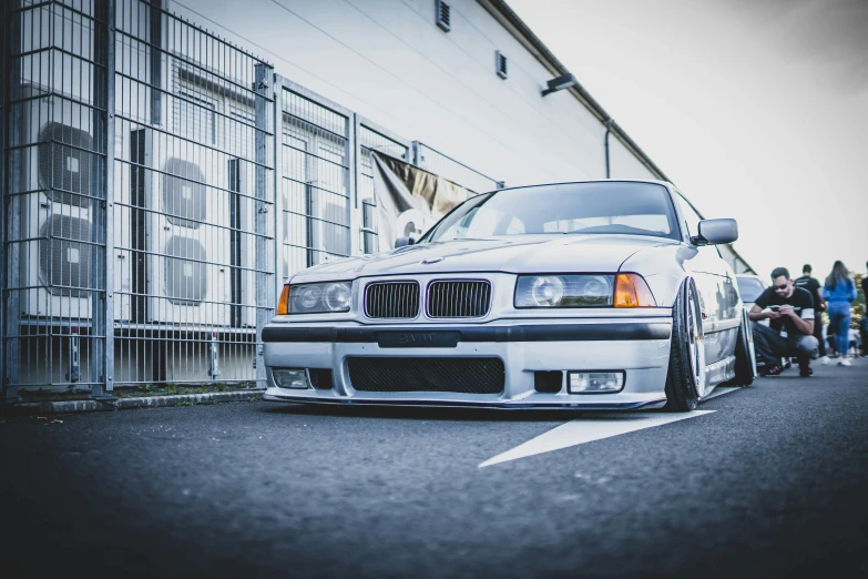 white bmw parked beside a group of people