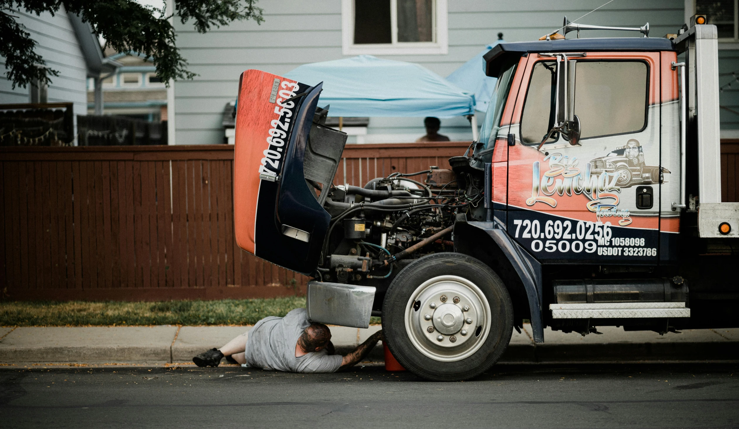 a man laying on the ground next to a truck, by Ryan Pancoast, unsplash, photorealism, repairing the other one, crying engine, washington dc, thicc build