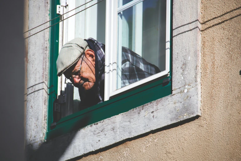 a man that is looking out of a window, pexels contest winner, photorealism, lisbon, old man doing hard work, visor covering eyes, pareidolia