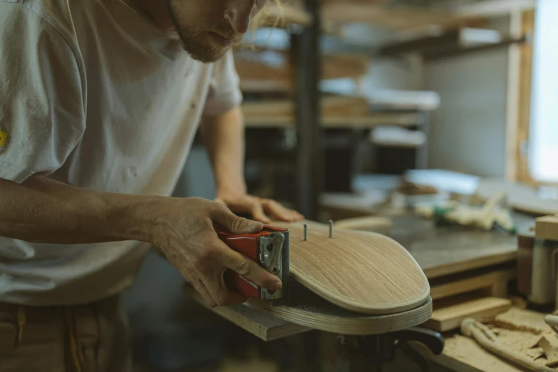 a man working on a skateboard in a workshop, an album cover, pexels contest winner, guitar shape build, stitching, thumbnail, woodturning