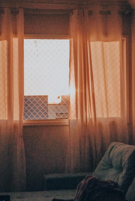 a view of the sun through the curtains from a window