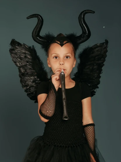 a little girl dressed as an angel singing into a microphone, an album cover, by Winona Nelson, pexels contest winner, hurufiyya, horns. dark colors, animatronic angelina jolie, authentic costume, toothless