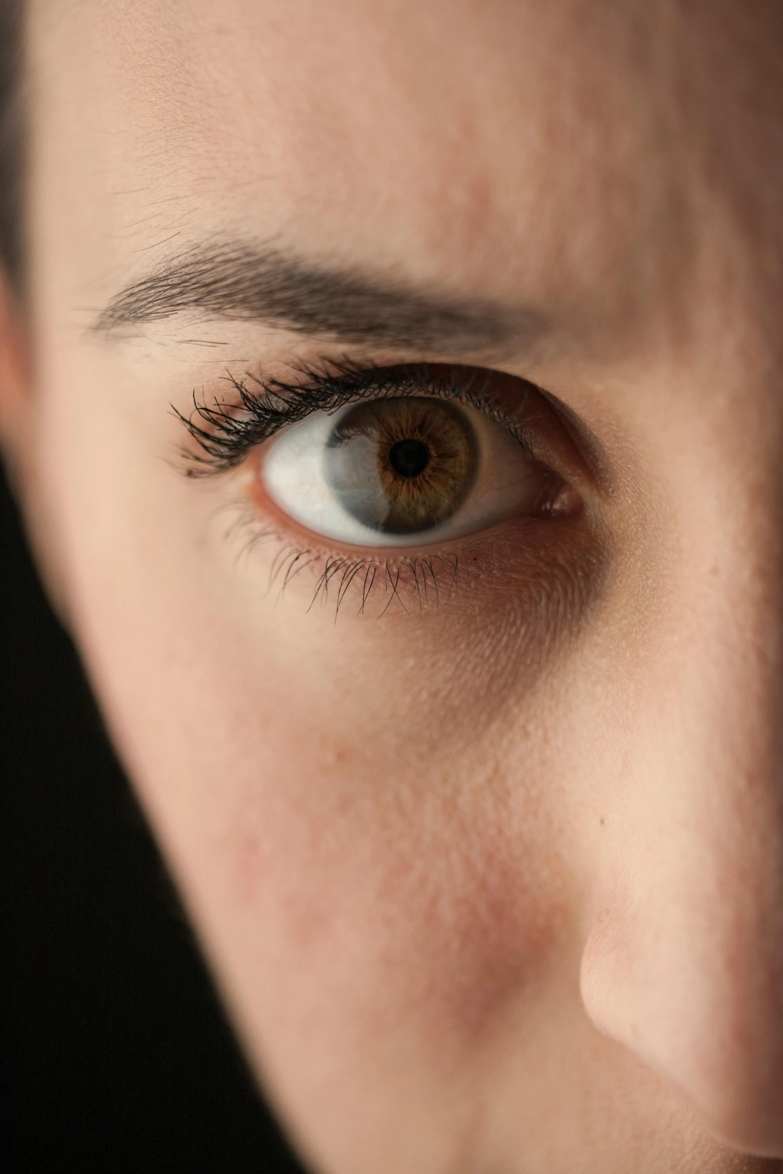 a close up of a person with a cell phone, by Adam Marczyński, trending on pexels, hyperrealism, brown almond-shaped eyes, with a black background, eye of a woman, alert brown eyes