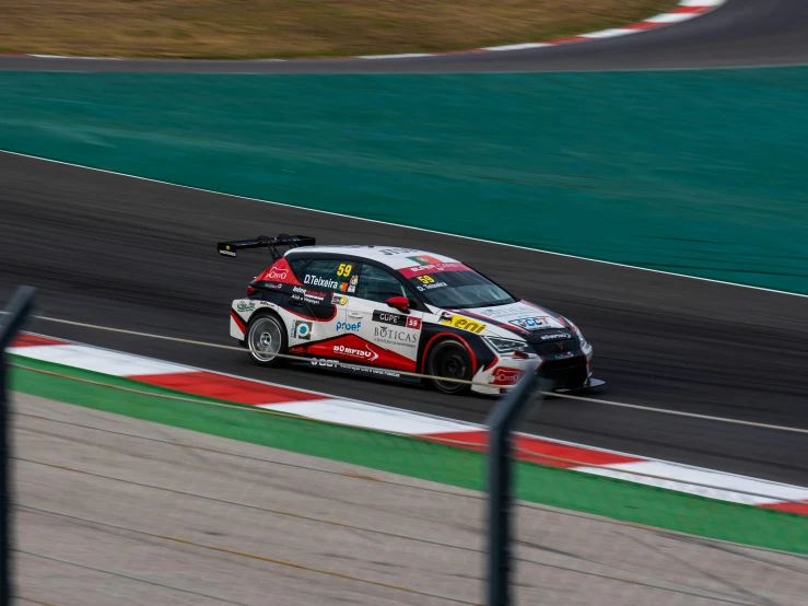 the car races on the track with a fence in front of it