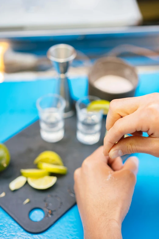 a close up of a person cutting limes on a cutting board, getting his tacos and drink), partially cupping her hands, beach setting, vodka