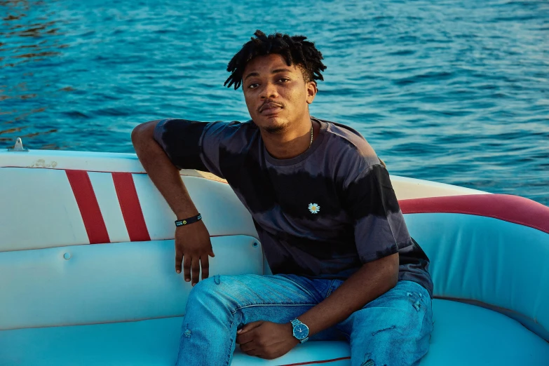 a young man sitting on top of a boat near the water