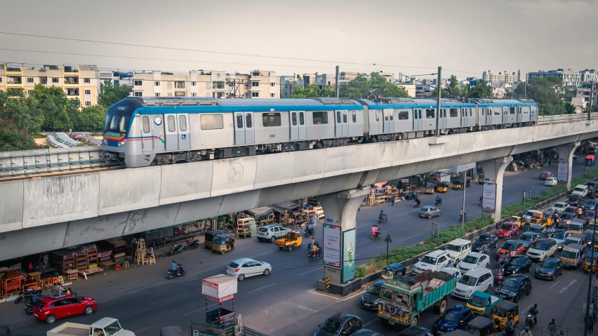 a blue and white train traveling over a bridge, samikshavad, in busy city, avatar image