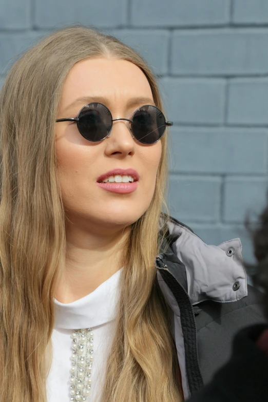 a woman with long blonde hair wearing sunglasses, sydney sweeney, journalism photo, looking to his side, street photo