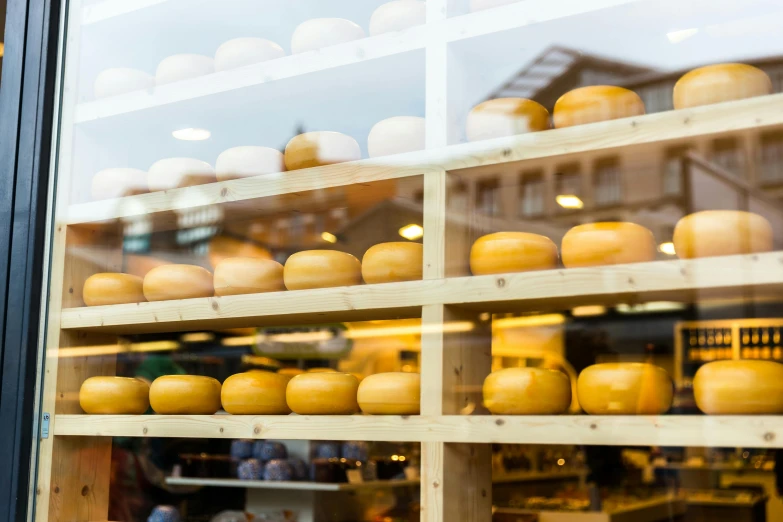 a store window filled with lots of cheese, by Julia Pishtar, trending on unsplash, fan favorite, round buildings in background, golden windows, panoramic