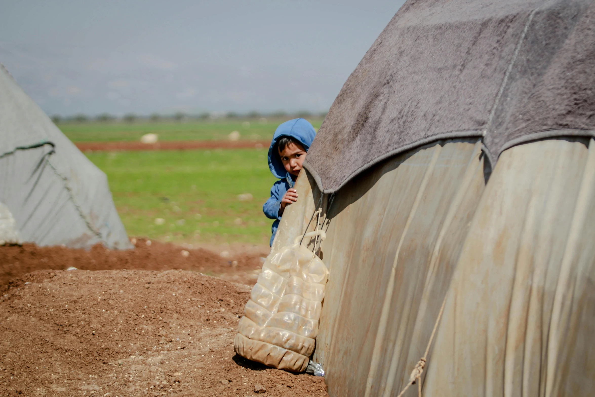 a little boy that is standing in the dirt, hurufiyya, tents, profile image, plastic and fabric, take cover