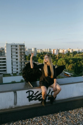 a woman sitting on top of a building, an album cover, inspired by Elsa Bleda, pexels contest winner, has black wings, russian girlfriend, rooftop party, blonde