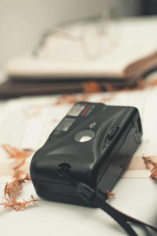 a camera sitting on top of a table next to a book, toy camera