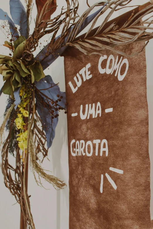 a close up of a sign on a door, by Nándor Katona, instagram, gutai group, displayed on an altar, style of carrivagio, unco corporate banner, brown flowers