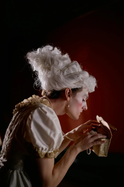 an elegantly dressed woman smelling a cookie while wearing a tiara