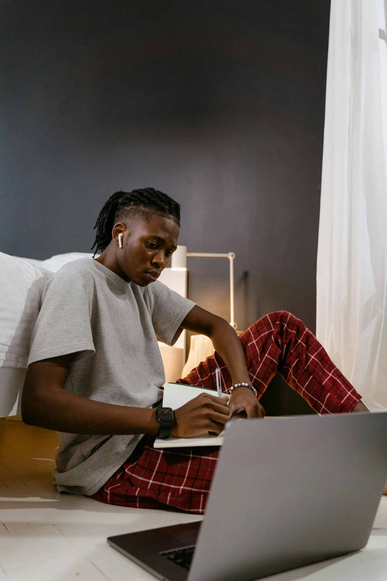 a man sitting on a bed using a laptop, by Chinwe Chukwuogo-Roy, trending on pexels, visual art, androgynous person, chief keef, performing, trying to read