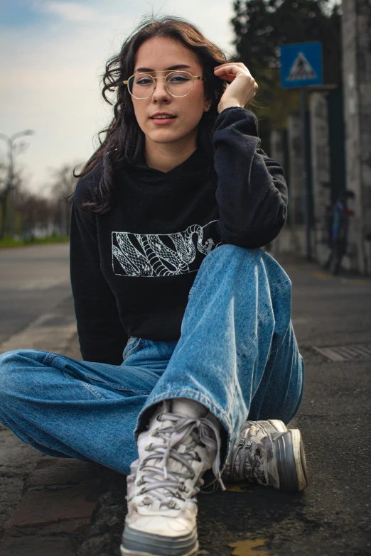 a woman with glasses sits on the side of the road