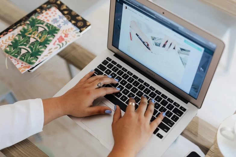 a close up of a person typing on a laptop, a computer rendering, by Julia Pishtar, trending on pexels, ornate designs on desk, bottom angle, holding pencil, full figure