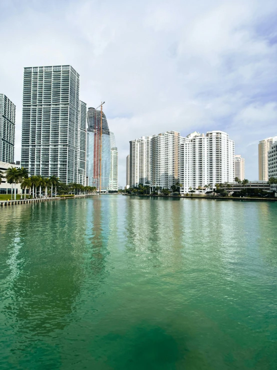 large white buildings and blue sky reflect off the water