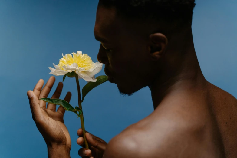 a man with an unkempt shirt is holding up a yellow and white flower