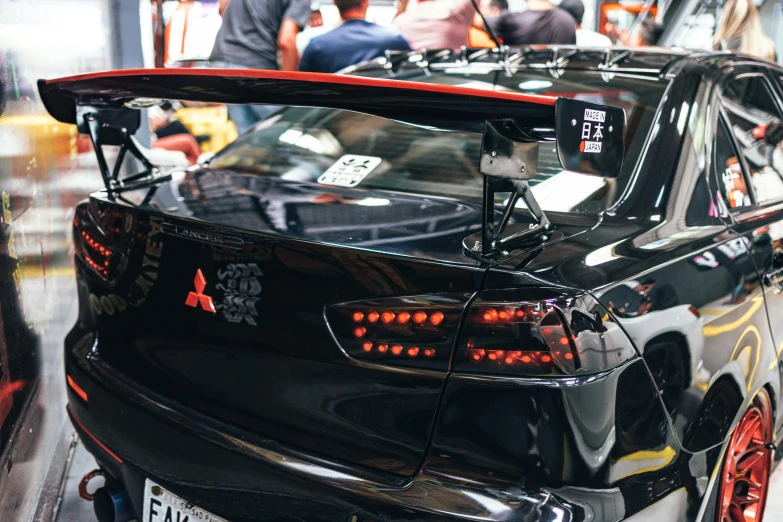 a black car sitting in a display case next to people