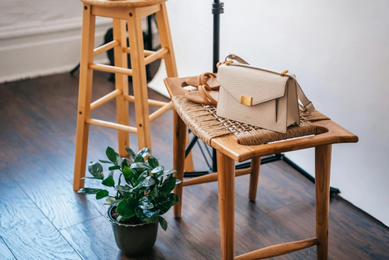 the purse is sitting on the chair next to the wooden stool