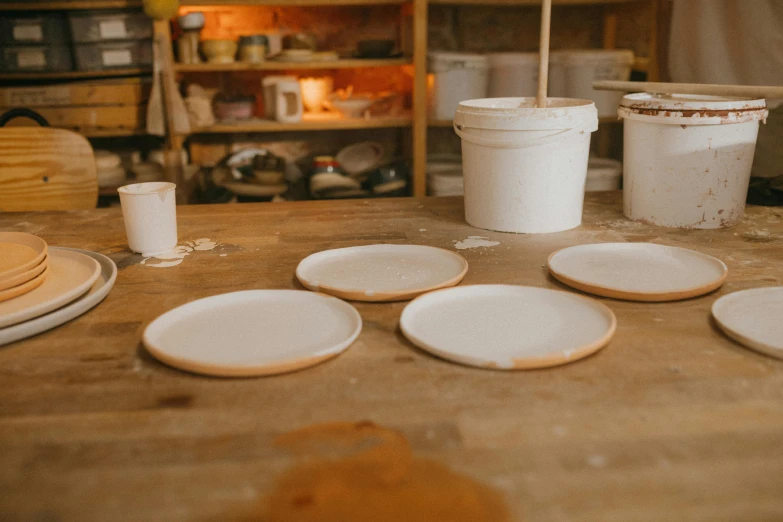 a group of plates sitting on top of a wooden table, inspired by Lewis Henry Meakin, process art, white clay, high quality product image”, filling the frame, ivory and copper