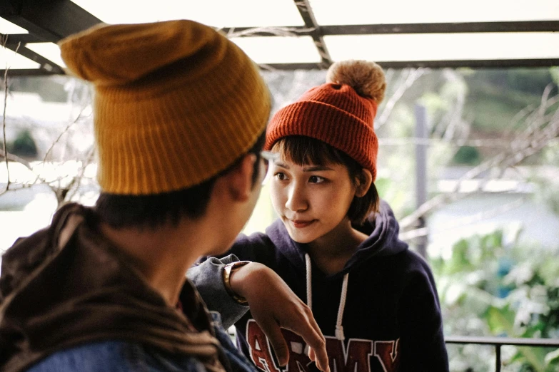 a couple of people standing next to each other, inspired by Kaii Higashiyama, trending on pexels, beanie, female actress from korea, dialogue, warm coloured