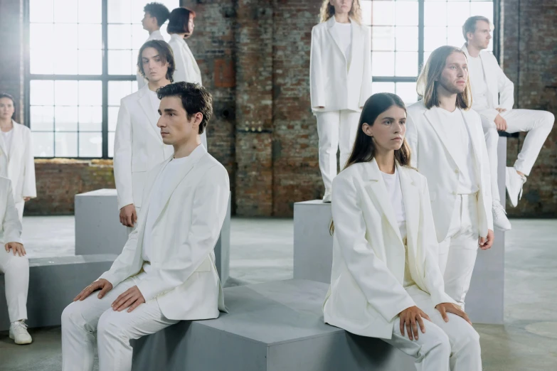 a group of people sitting next to each other, inspired by Vanessa Beecroft, bauhaus, wearing a white tuxedo, outlive streetwear collection, in formation, focus in the foreground