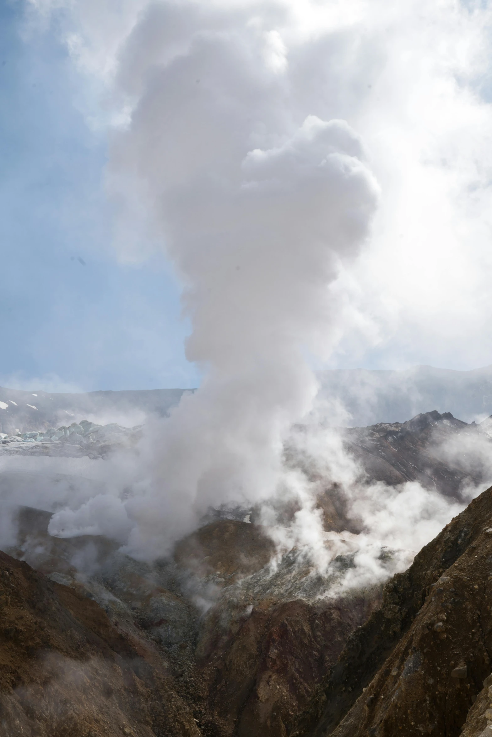 a hill covered in steam and a mountain with a sky background