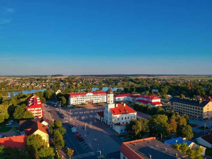 an aerial view of a town with a river in the background, by Adam Marczyński, square, blue sky, shot at golden hour, white