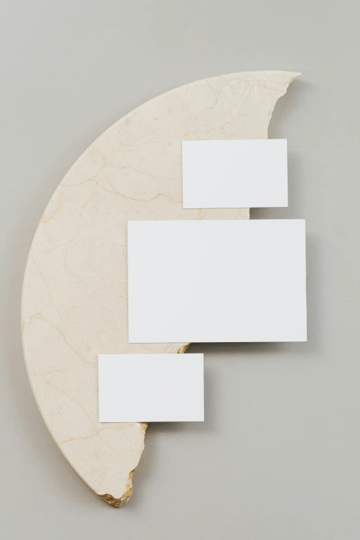 a piece of wood sitting on top of a table, an abstract sculpture, inspired by Isamu Noguchi, unsplash, made of all white ceramic tiles, crescent moon, whiteboards, silver，ivory