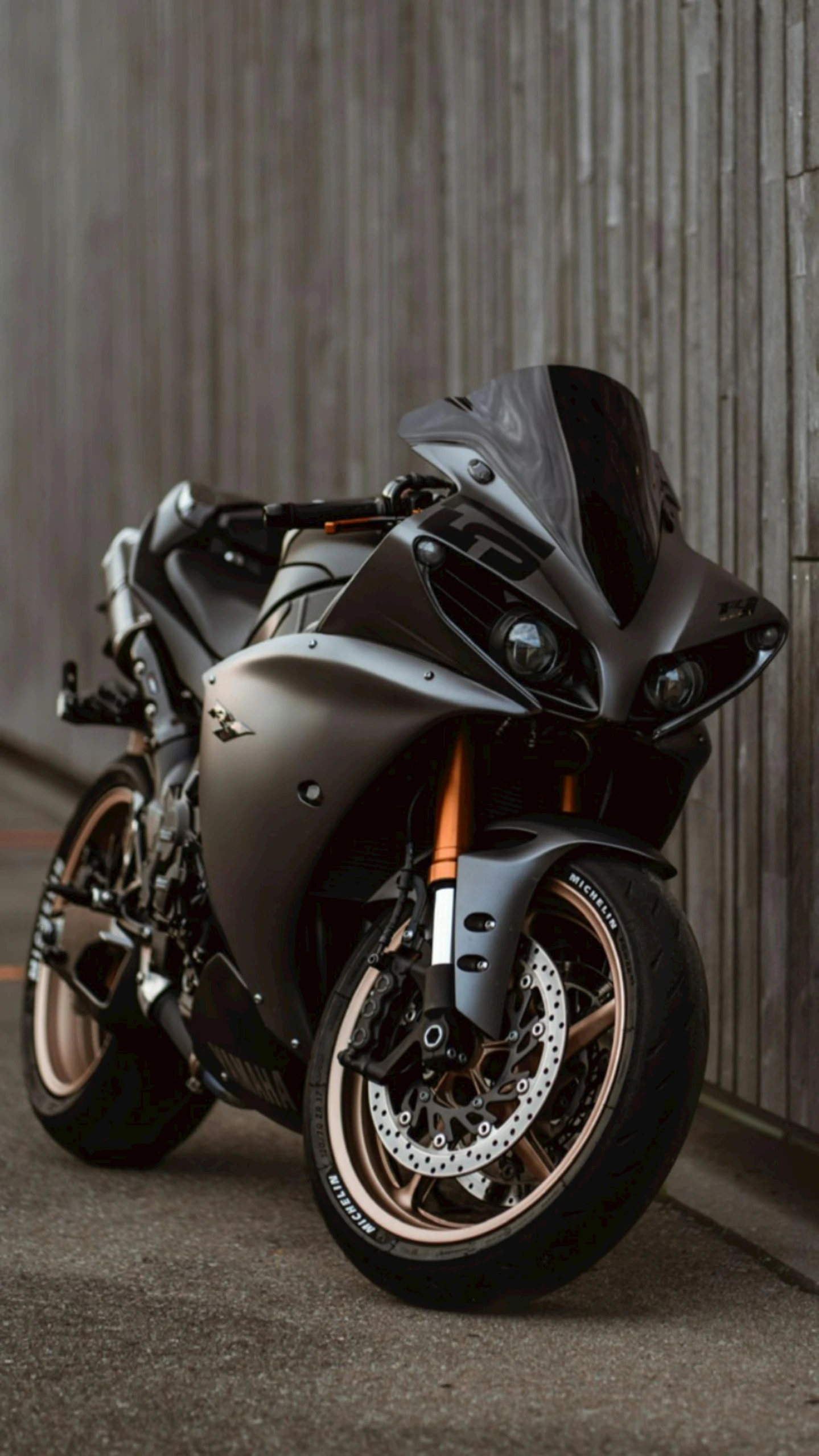 a black motorcycle parked next to a wall, grey and dark theme, thumbnail, carbon fiber, brown:-2