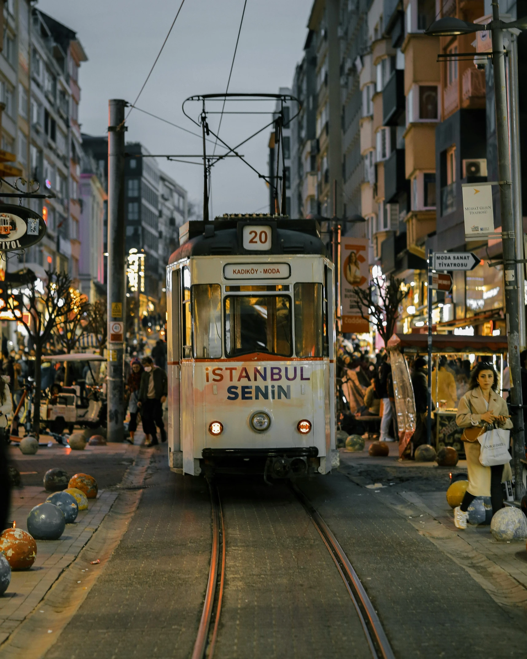 a trolley traveling down a street next to tall buildings, by Micha Klein, unsplash contest winner, art nouveau, turkey, lgbt, evening time, underground