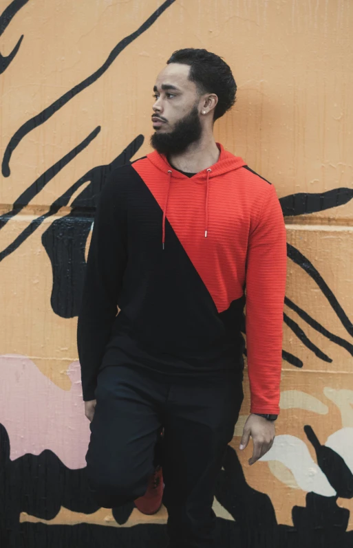 a man that is standing in front of a wall, inspired by Paul Georges, pexels contest winner, red and black cape and hoodie, geometric, pete davidson, kano)