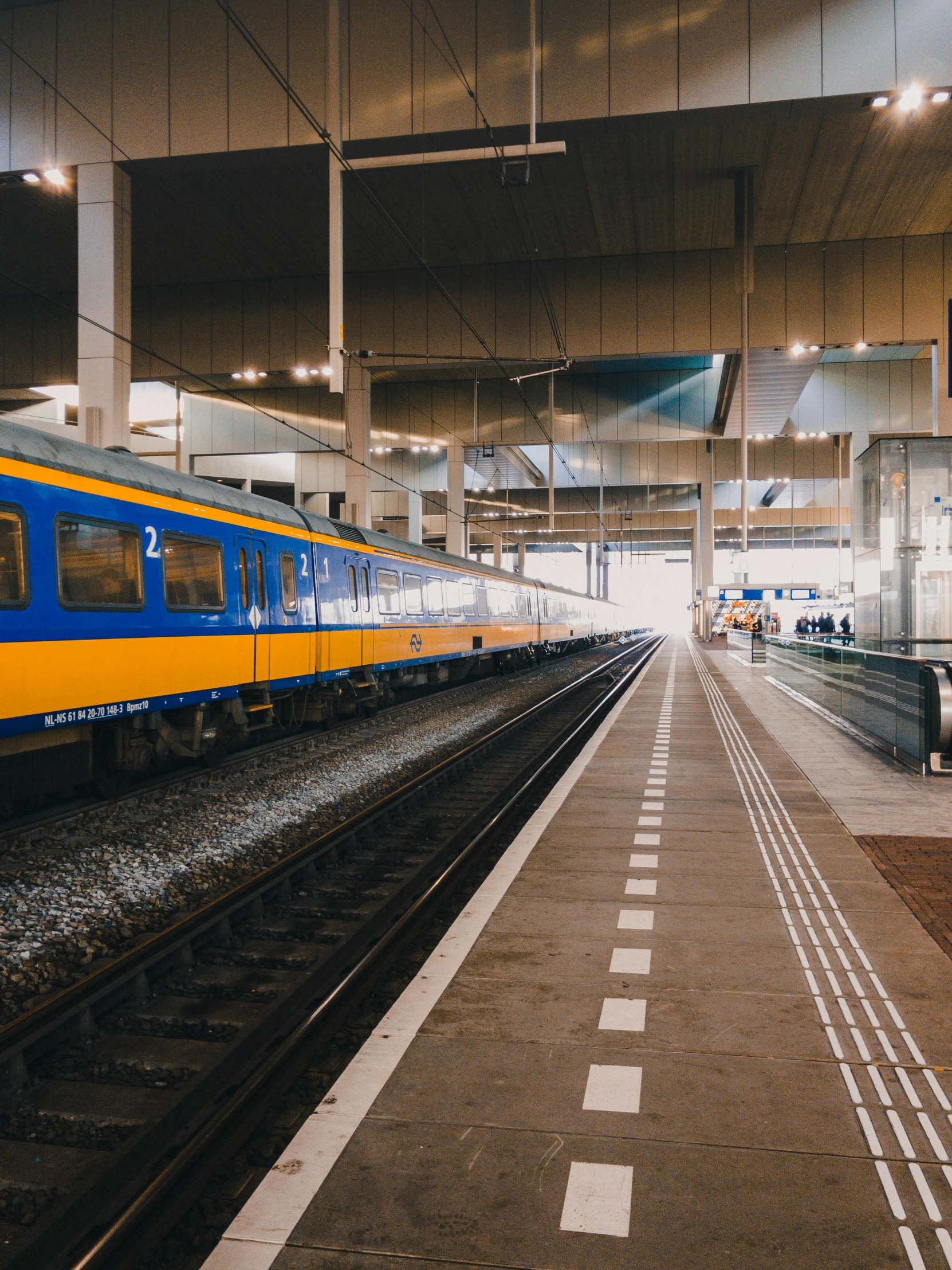 a blue and yellow train at a train station, by Andries Stock, pexels contest winner, delft, 🚿🗝📝, panoramic, 2 5 6 x 2 5 6 pixels