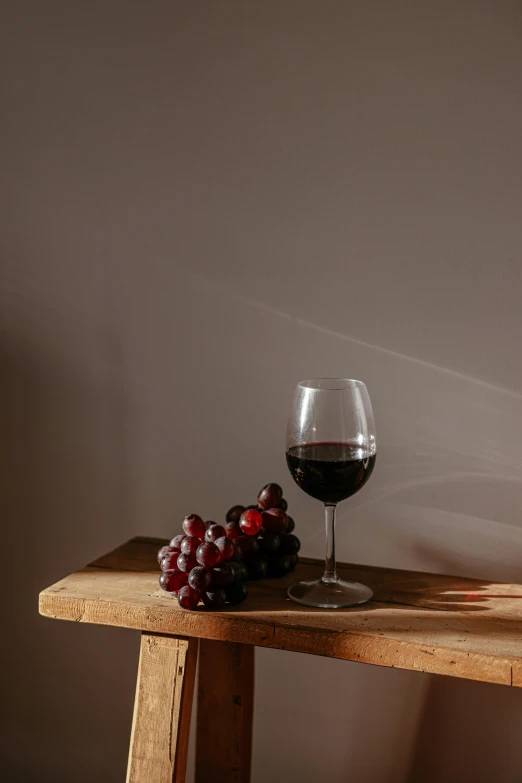 the small, wooden table holds a glass and a bunch of gs