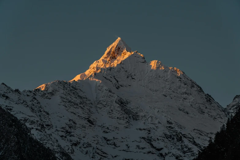 a mountain's snow capped peak with the sun setting on it