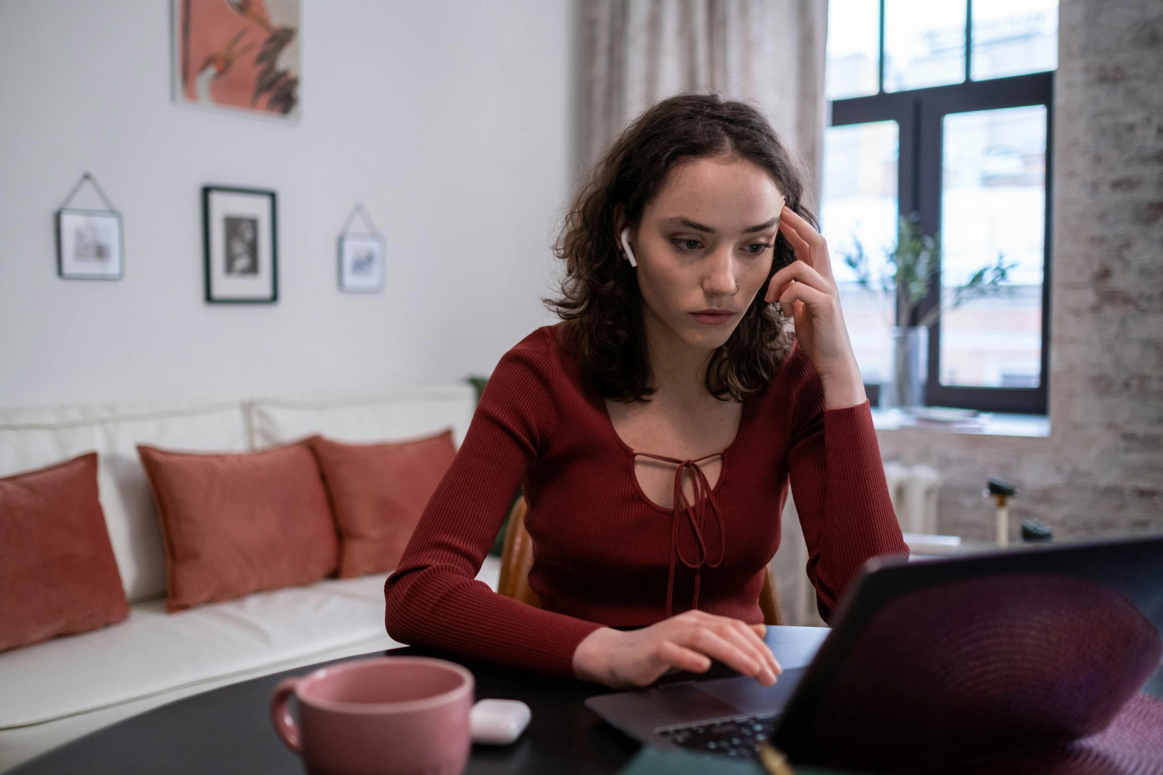 a woman sitting at a table in front of a laptop, slightly red, mental health, worksafe. instagram photo, girl making a phone call