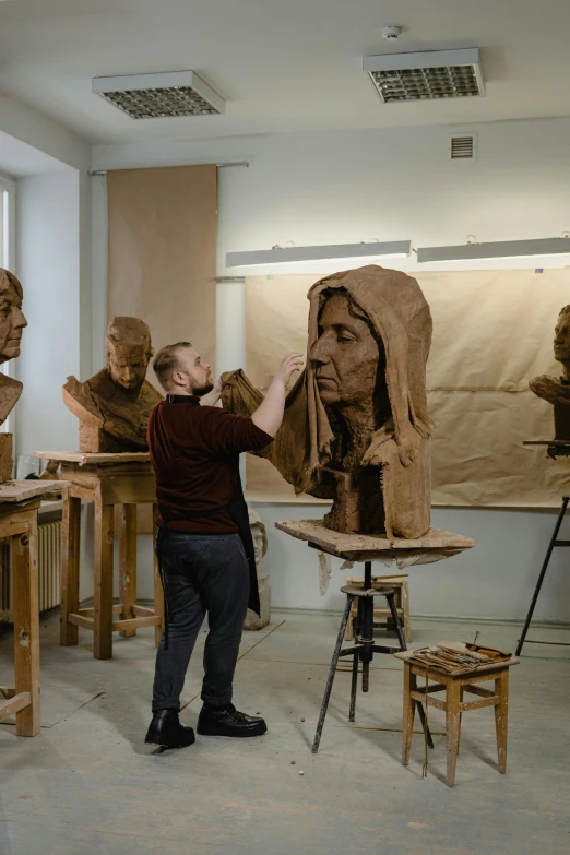 a man working on a sculpture in a studio, by Ilya Ostroukhov, academic art, full faces, hood, trending artwork, made of cardboard