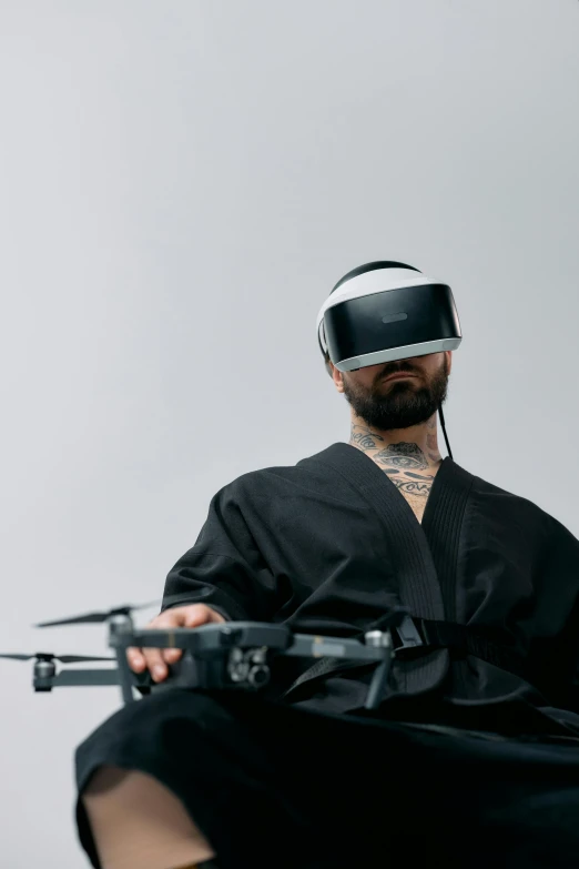 a man sitting in a chair with a remote control, inspired by Kanō Naizen, unsplash, afrofuturism, vr helmet on man, picture of a male biker, tech robes, pictured from the shoulders up