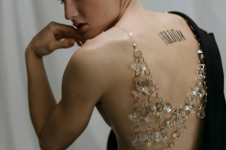 a woman with a tattoo on her back, inspired by Nina Hamnett, fluxus, made of crystals, transparent, chain, upcycled