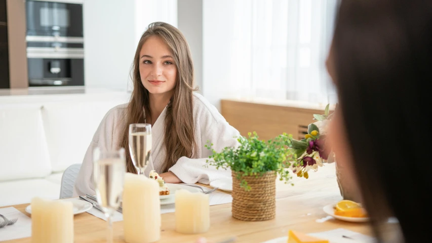 a woman sitting at a dinner table, looking back to the camera