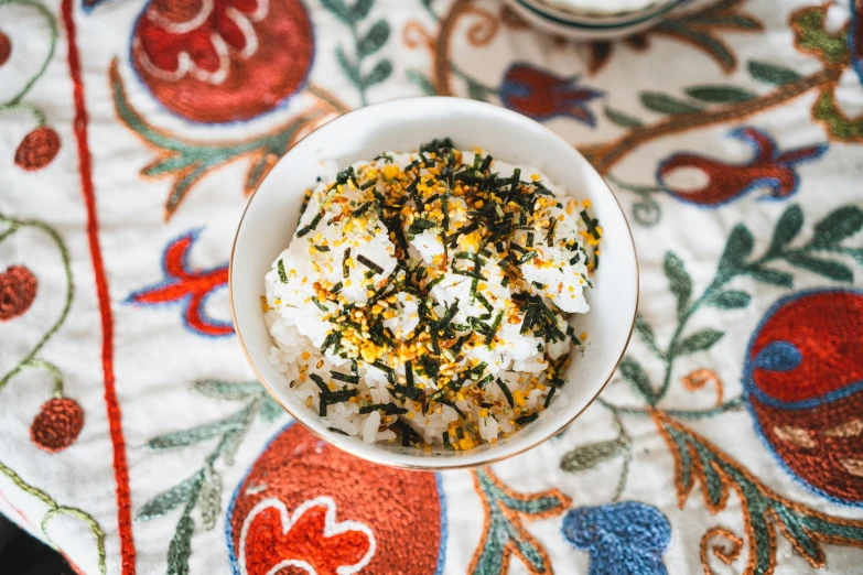 a bowl with food is on a multicolored table cloth